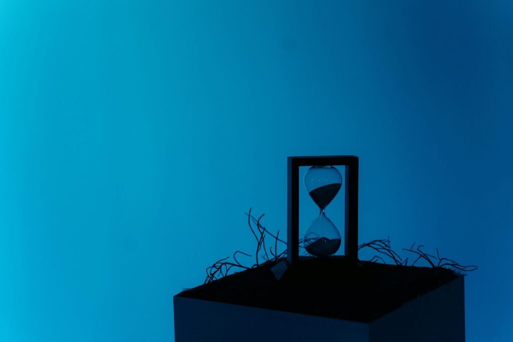 A minimalist hourglass set against a vibrant blue backdrop, representing the passage of time.